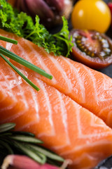 Portion of fresh salmon with spices,herbs and vegetables on blac