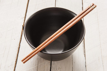 chopsticks lying across an empty bowl that is sitting on a plate
