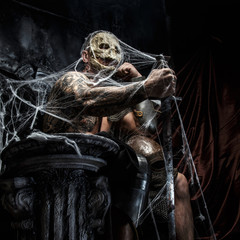 Muscular man with skull on his face.