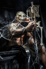 Muscular man with skull on his face.