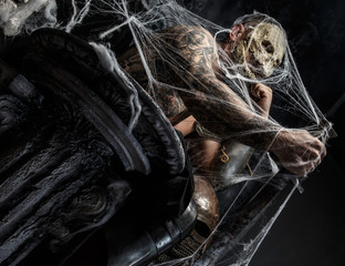 Muscular man with skull on his face.