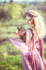 Beautiful blonde girl in a pink dress has got a bouquet