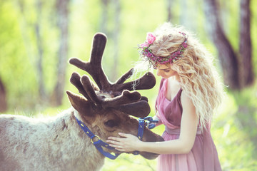Portrait of a girl in a fairy dress next to a reindeer