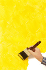 Partly painted yellow wall unfinished with man painting with paintbrush in hand photo