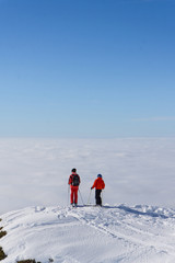 Fototapeta na wymiar Two skiers on top of mountain above the clouds