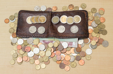 thai baht coin and paper with brown leather wallet on plywood ba