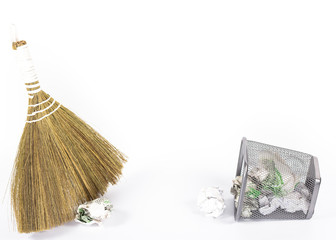 isolated broom and wastebasket full of waste newspaper