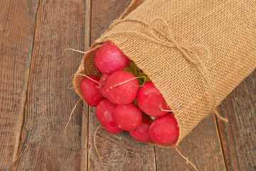 Big bunch of radish wrapped in canvas on wooden background
