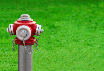 Modern red hydrant on a green grass background