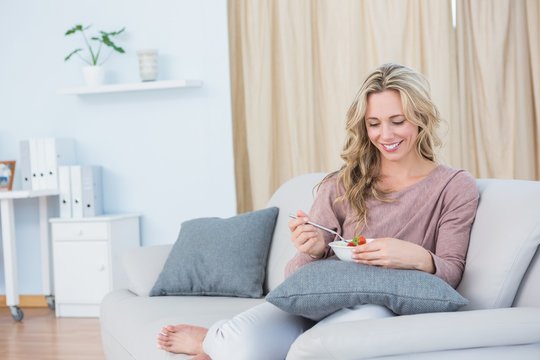Happy blonde on couch eating salad