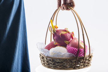 Woman hand carrying a  basket full of fruits.