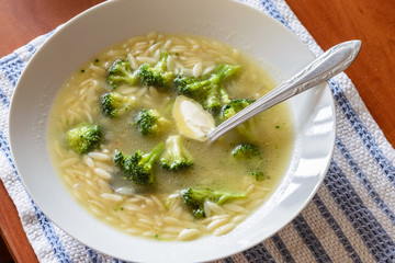 Soup with broccoli cabbage, rice pasta and butter in warm chicken broth
