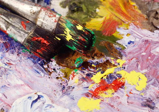 Art still life - two paintbrushes and dirty palette with colourf