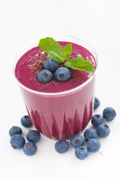 blueberry milkshake in a glass on white table, close-up