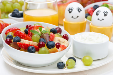 fresh fruit salad, cream and painted eggs for breakfast, closeup