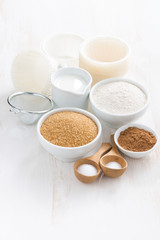 Ingredients for baking muffins on white table, vertical