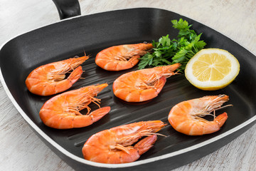 cooked shrimps with lemon and parsley in a pan