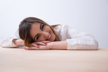 Obraz premium Portrait of a young smiling woman lying on the table