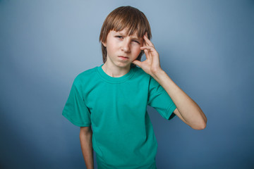 European-looking boy of ten years headache, migraine on a gray b