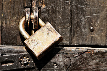 Old wooden door locked with padlock.