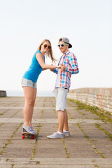 smiling couple with skateboard outdoors