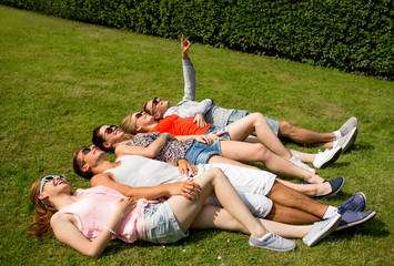 group of smiling friends lying on grass outdoors