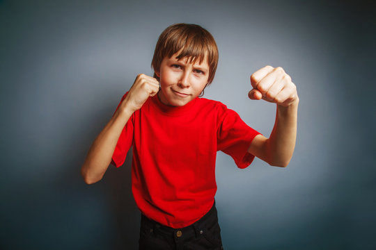 European-looking boy of ten years shows a fist, anger, threat on