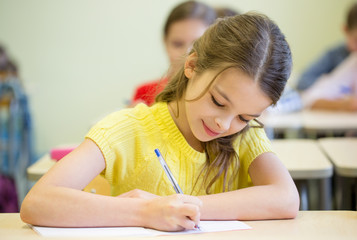 group of school kids writing test in classroom