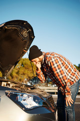 Brutal male looking at broken car vehicle engine and throws up