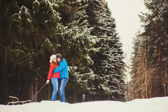Happy couple hugging on a hill in the winter park