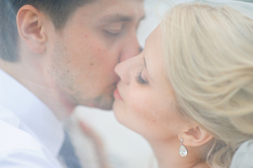 love the bride and groom are covered with a veil and kiss