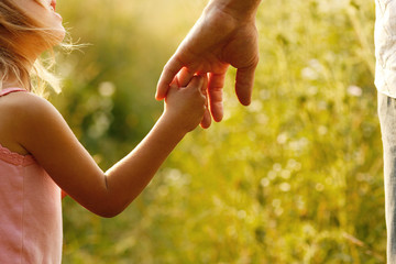 parent holds the hand of a small child