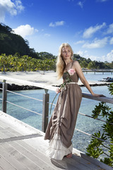 beautiful woman in a long dress on wooden bridge near sea.