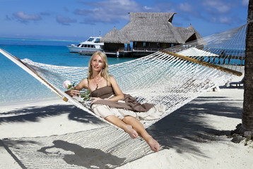 woman in a long sundress in a hammock on a sea background
