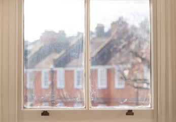 Old white window frame of victorian house with view of tenements