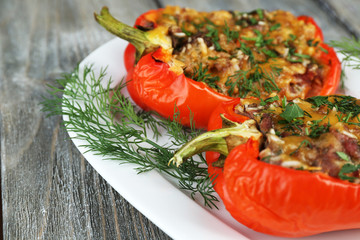Stuffed red peppers with greens on plate on wooden table