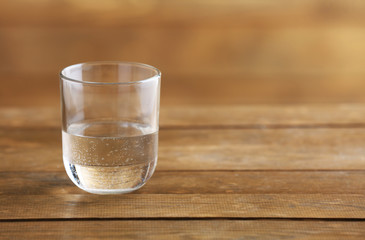 Glass of clean mineral water on rustic wooden background