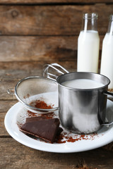 Metal mug and glass bottles of milk with chocolate chunks and