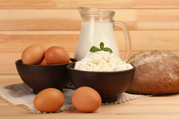 Cottage cheese in clay bowl with jug of milk, loaf of bread