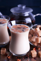 Black tea with milk in glasses and teapot with lump sugar