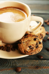 Cup of coffee and tasty cookies on wooden background