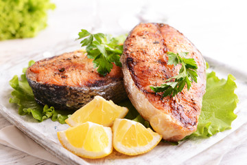 Tasty baked fish on plate on table close-up