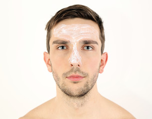Obraz premium Handsome young man with cream lotion on face isolated on white