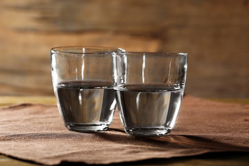 Two glasses of water on table on wooden background