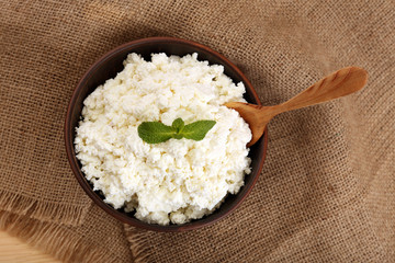 Cottage cheese in bowl on sackcloth background