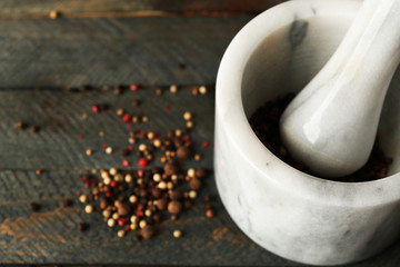Mixture of peppers in mortar on wooden background