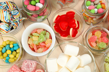 Sweetness in different containers on wooden background