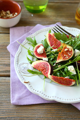 Salad with arugula, figs and cheese on white plate