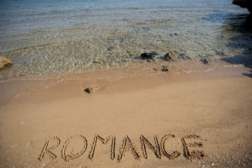 Word romance written in sand