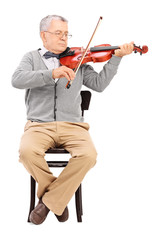 Senior gentleman playing a violin seated on a chair